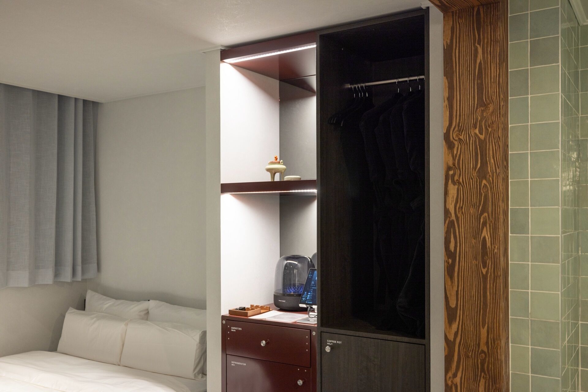 A hotel room with a bed, a wardrobe, a coffee pot, and a minibar.