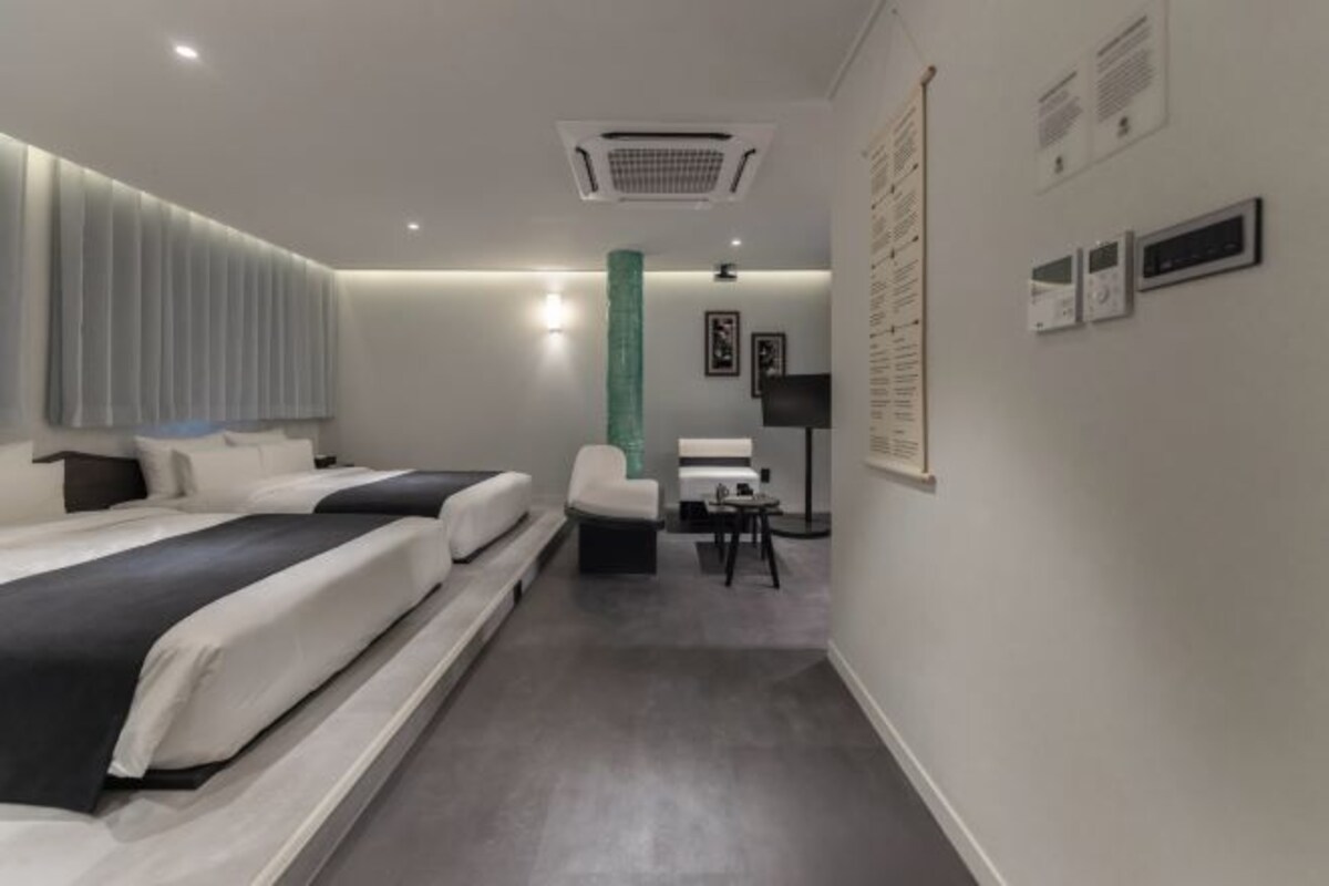 Una habitación de hotel moderna con dos camas, una zona de estar y un escritorio.