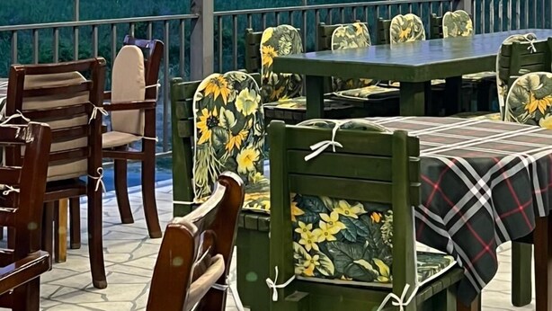 An outdoor patio with wooden chairs and tables, a view of the ocean, and a sunset sky. - Rahat  (Khachmaz)