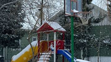 A playground with a slide and a climbing structure in a snowy setting.