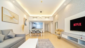 A modern living room with a sofa, coffee table, and a TV mounted on the wall displaying 'NETFLIX'. - Zapbed House - SP 803 (Dubai)