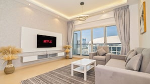 A modern living room with a flat-screen TV, a sofa, a coffee table, and a large window with a city view. - Zapbed House - SP 803 (Dubai)