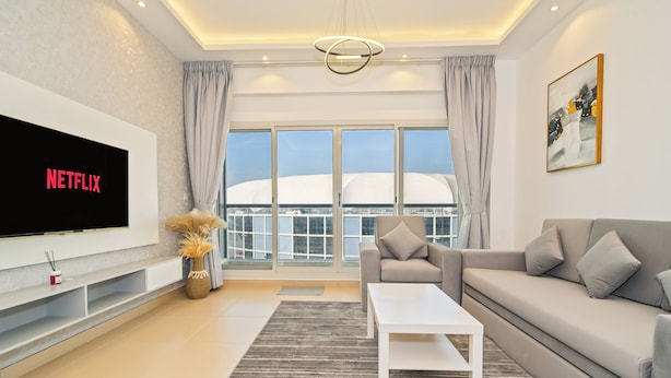 A modern living room with a large flat-screen TV, a sofa, a coffee table, and a view of a white dome structure through large windows. - Zapbed House - SP 803 (Dubai)