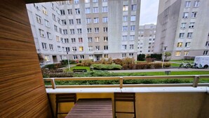 Ein Balkon mit Holztisch und Stühlen, der auf ein Wohngebiet mit Wohngebäuden und einer Straße blickt.