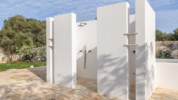 Une entrée extérieure moderne avec des murs blancs et un portail en métal.
