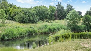 A serene riverside park with a metal fence, lush greenery, and trees. - 3 bedroom accommodation in Faringdon (Faringdon)