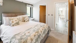 A bedroom with a large bed, a window, a door, and a hallway. - 3 bedroom accommodation in Faringdon (Faringdon)