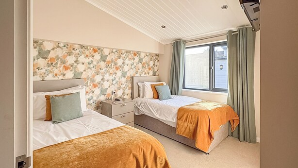 A bedroom with two beds, a floral headboard, a window with curtains, and a ceiling with recessed lighting. - 3 bedroom accommodation in Faringdon (Faringdon)