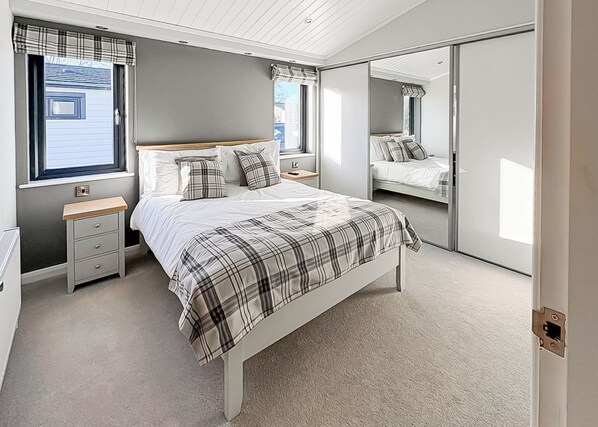 A bedroom with a bed, bedside tables, a wardrobe, and a window with curtains.