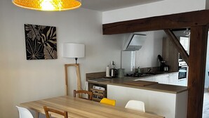 A modern kitchen with a wooden island, white cabinets, and a hanging pendant light. - Enjoy a cozy setting with a stunning view of the majestic Sées Cathedral. (Sées)