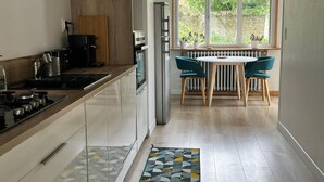A modern kitchen with a central island, a dining area with a table and chairs, and a large window providing natural light. - Enjoy a cozy setting with a stunning view of the majestic Sées Cathedral. (Sées)