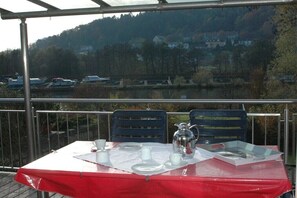 Enjoy a romantic meal for two in this serene outdoor dining area overlooking a tranquil lake and forested hillside.