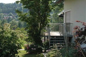 Enjoy a peaceful retreat with a balcony overlooking the surrounding landscape, surrounded by lush greenery and flowering plants.
