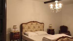 Un dormitori amb un llit de fusta, una làmpada penjant, una tauleta de nit i una cadira.