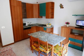 Een koelkast, een magnetron, een kookplaat, kookgerei, borden en bestek