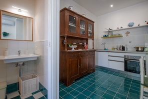 A kitchen with a sink, wooden cabinets, a dishwasher, and a tiled floor. - Casa Nostra - Private Sea View Garden (Praiano)