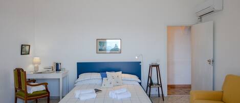 A hotel room with a bed, a desk, a chair, a small table, and a sofa.