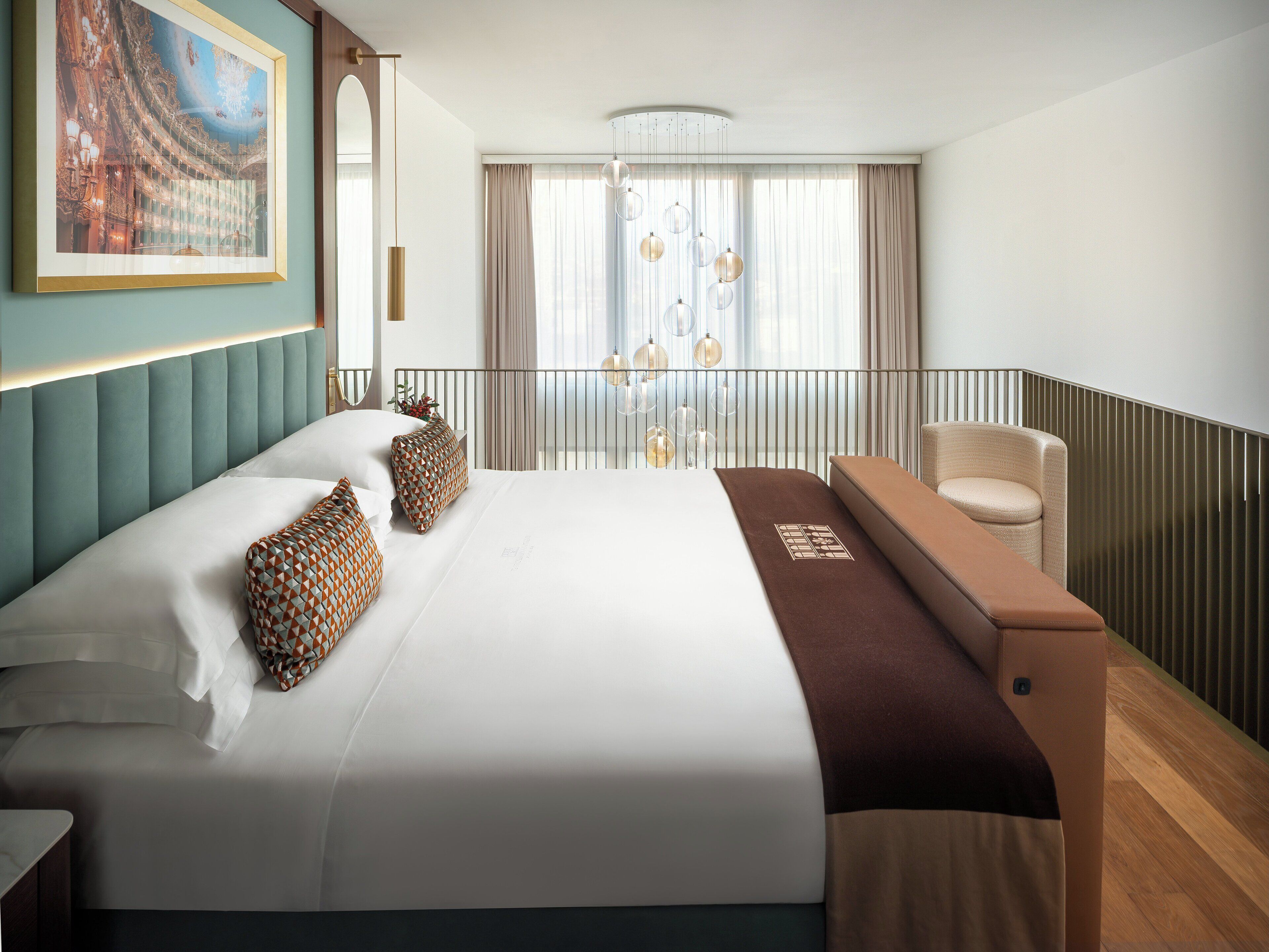 A hotel room with a large bed, a seating area, a balcony with a view, and a framed picture on the wall.