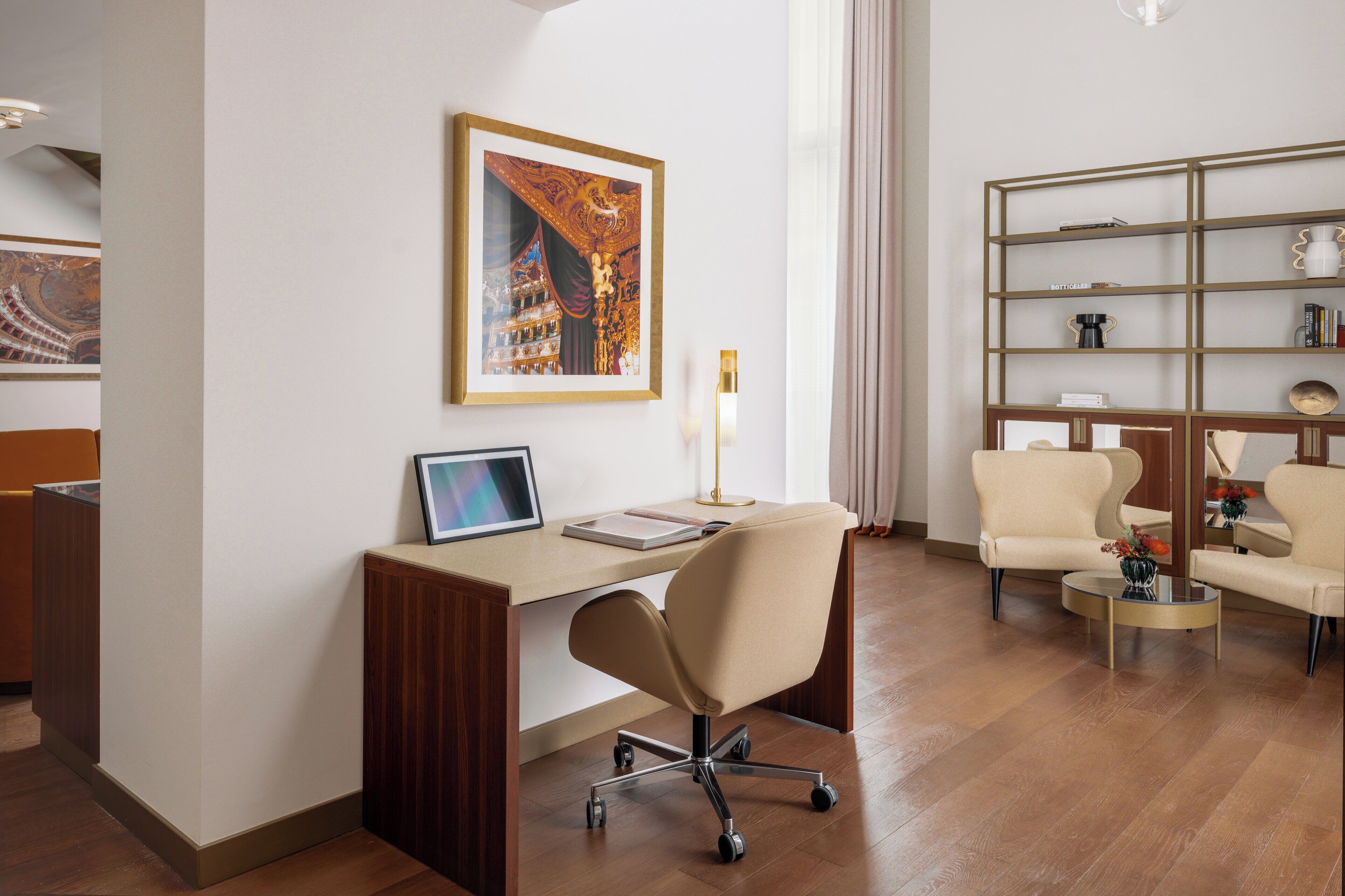 Una habitación de hotel moderna con un escritorio, un sillón cómodo, una estantería y un cuadro grande en la pared.