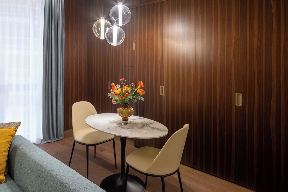 Een eetgedeelte met een ronde tafel, twee stoelen en een bloevas.