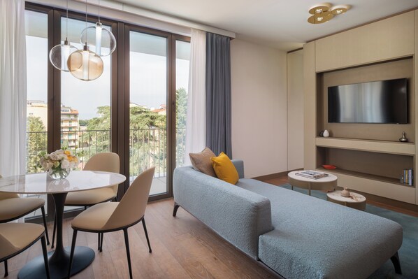 Un salon moderne comprenant un canapé, une table à manger, des chaises et un téléviseur.