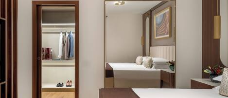Una habitación de hotel con cama, mesita de noche, espejo, armario y zapatero.
