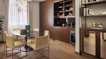 Een moderne eetruimte met een ronde glazen tafel, beige stoelen en een houten kast met planken.
