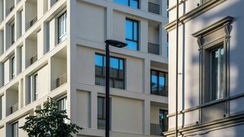 Ein mehrstöckiges Gebäude mit Balkonen, einer Straßenlaterne und einem Baum davor.
