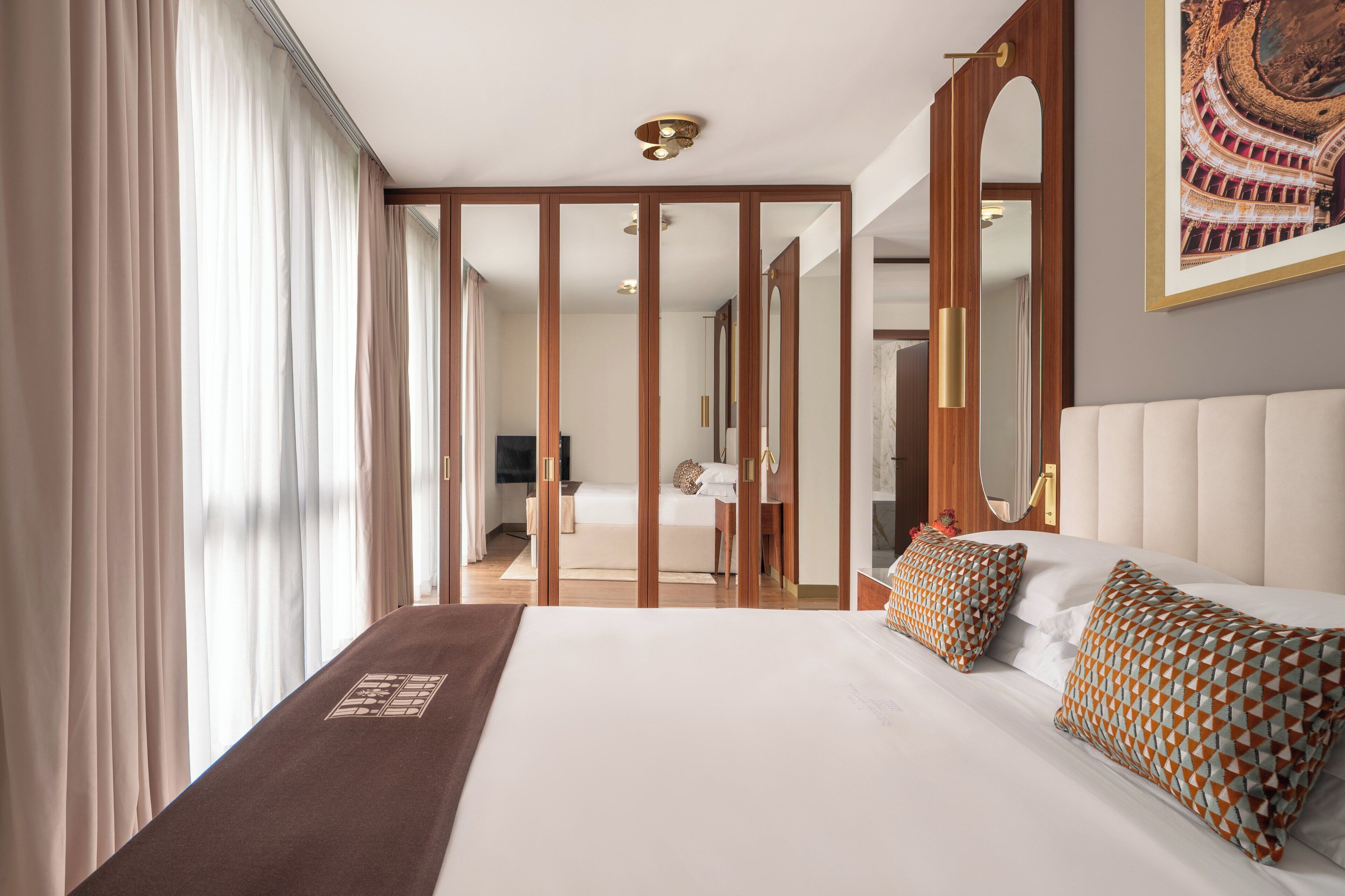 A hotel room with a large bed, a mirror, and a view of a hallway.