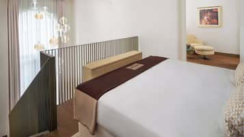 A hotel room with a bed, a bench, a chair, and a painting on the wall.