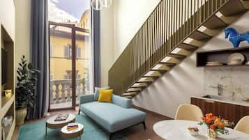 Una sala de estar moderna con un sofá azul, una mesa de comedor con un florero y una escalera decorada con un caballo azul.