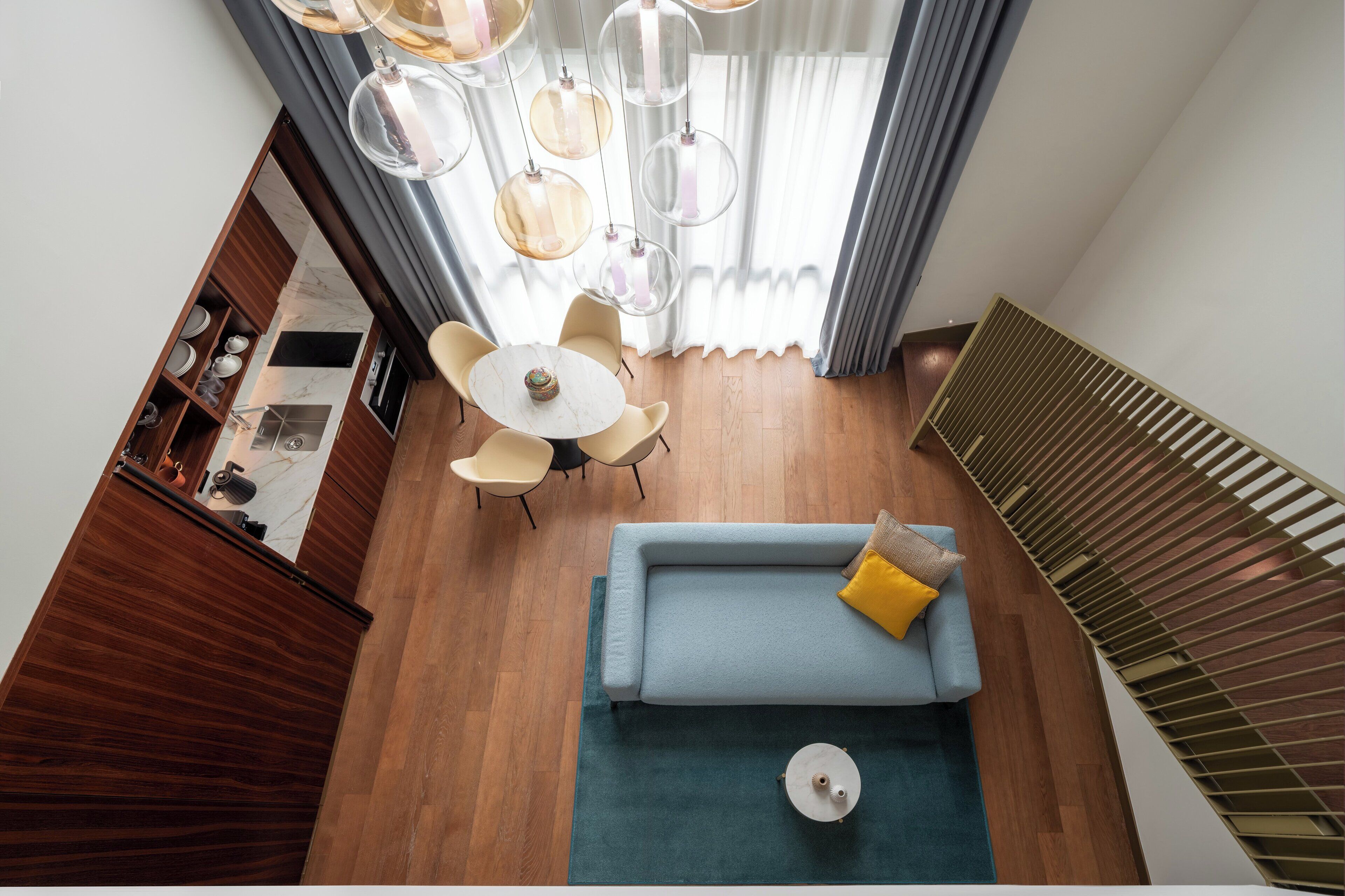 Een moderne woonkamer met een blauwe bank, een ronde salontafel en een eethoek met een witte tafel en stoelen.