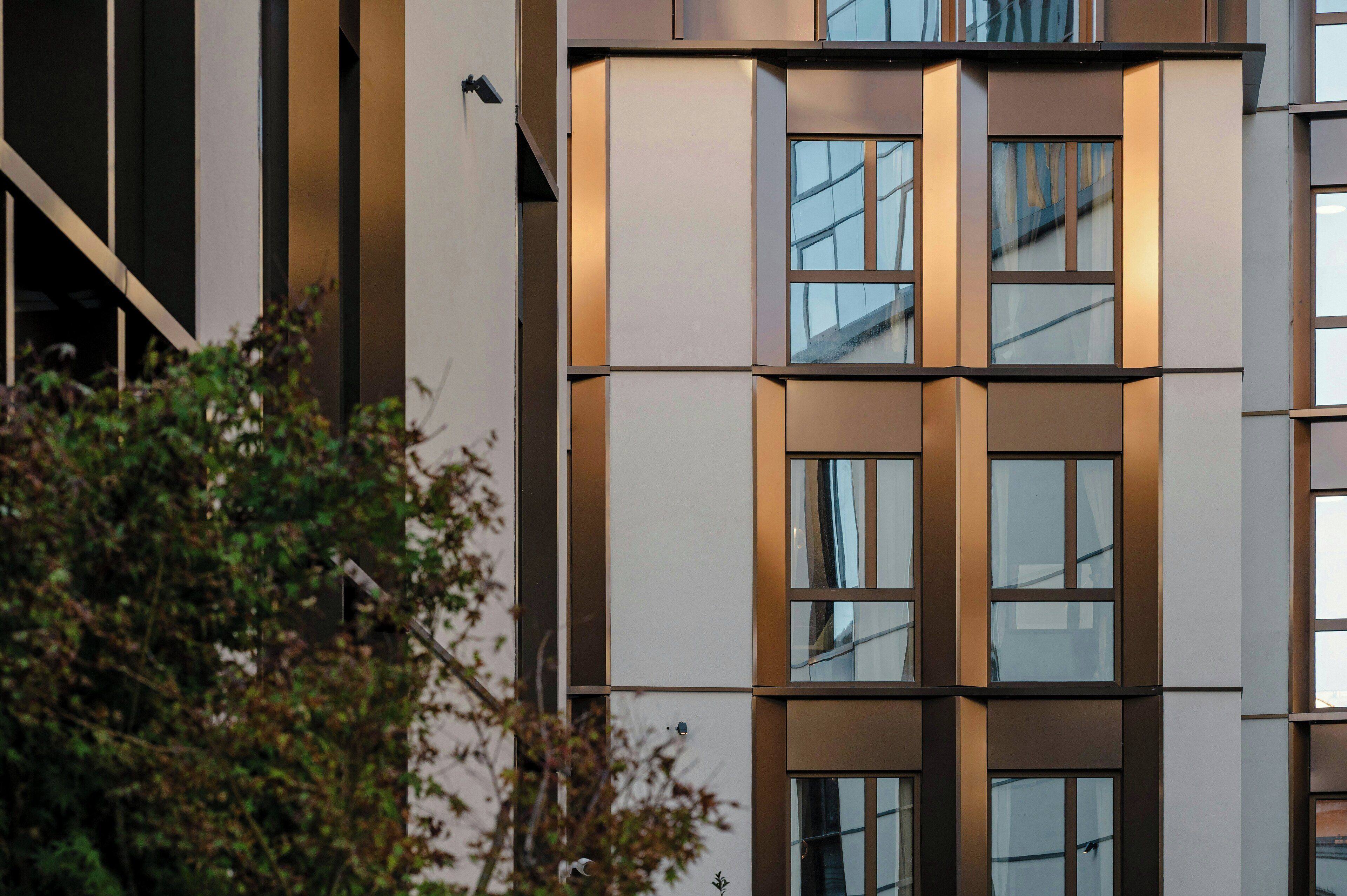 En byggnad med flera våningar och en modern arkitektonisk design, med stora fönster och en symmetrisk fasad.