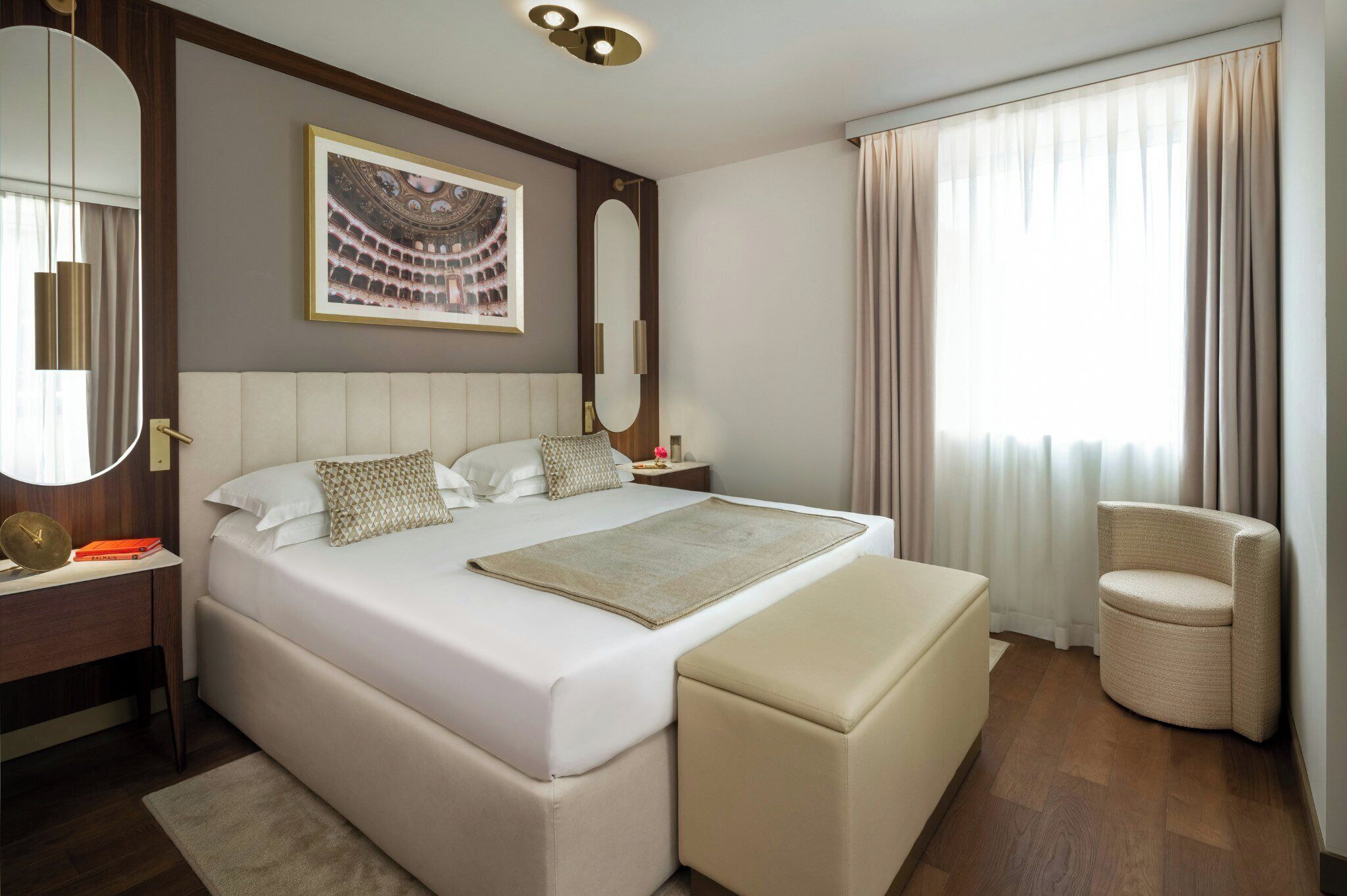 Une chambre d’hôtel moderne avec un grand lit, une table de chevet, une chaise et une grande fenêtre avec des rideaux.