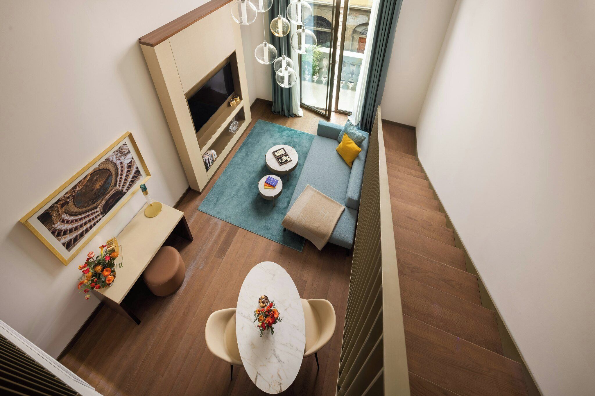 A compact living space with a sofa, a small table, a TV, and a balcony with a view.