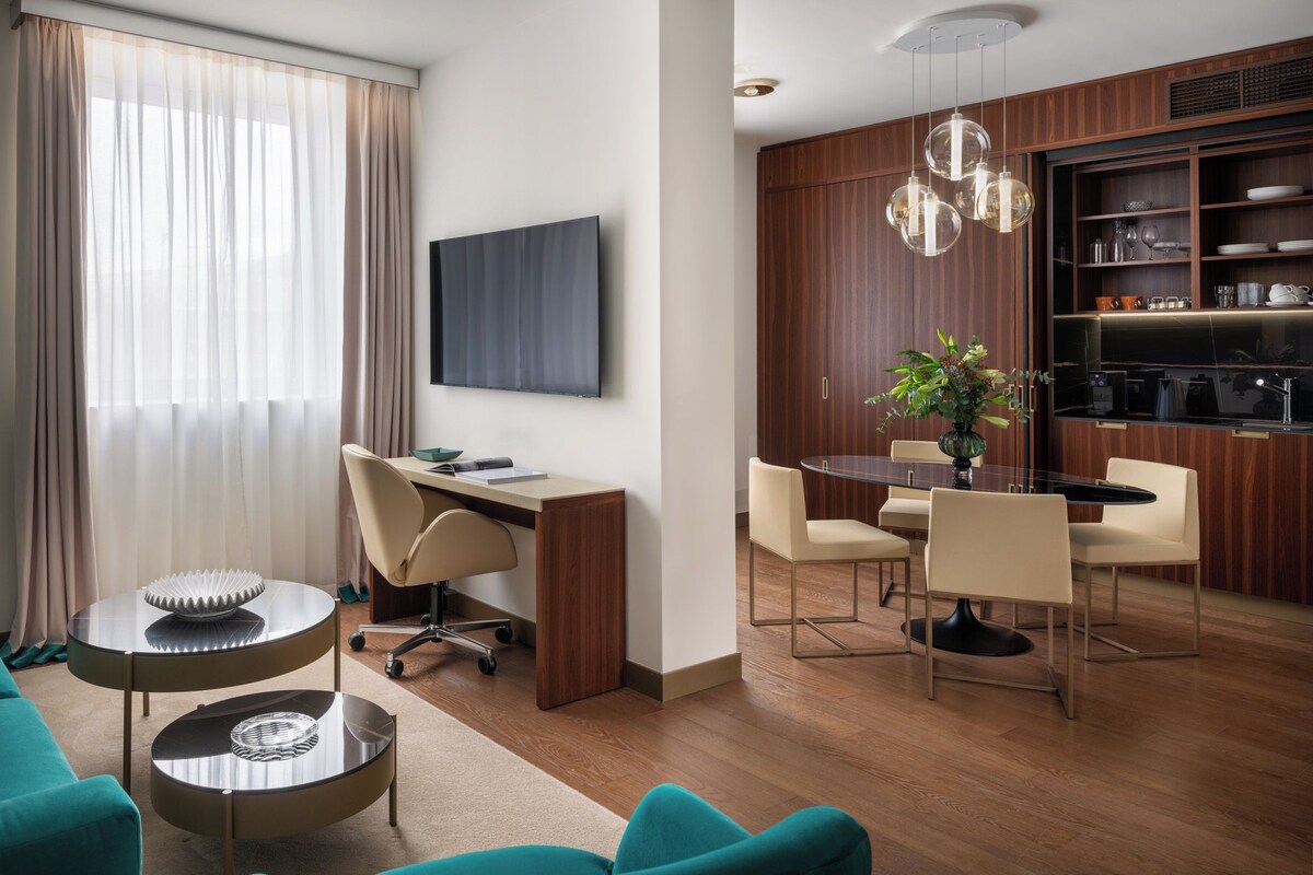 Een moderne woonkamer met een bank, een bureau en een eethoek met stoelen en een tafel.