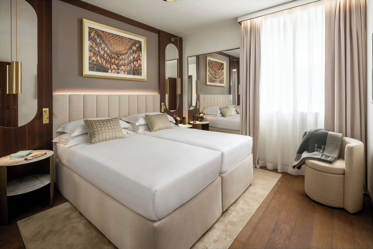 Una habitación de hotel con una cama grande, un espacio para sentarse, una mesita y un espejo.