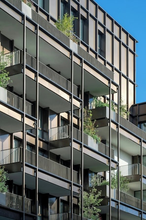 Un edificio de varios pisos con balcones, algunos con plantas.