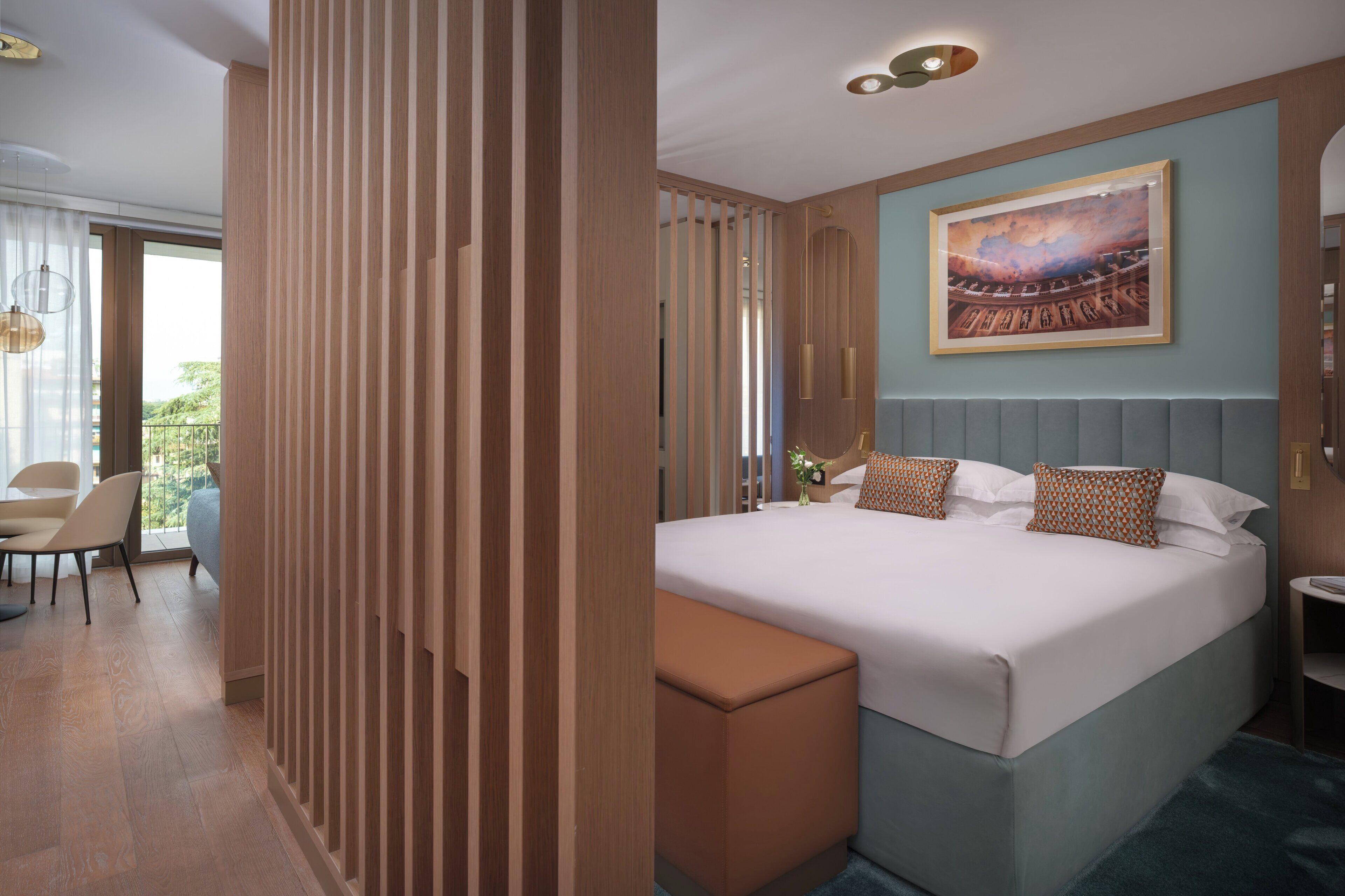 Une chambre d’hôtel moderne dotée d’un grand lit, d’un coin salon avec une chaise et une table, et d’un balcon offrant une vue agréable.
