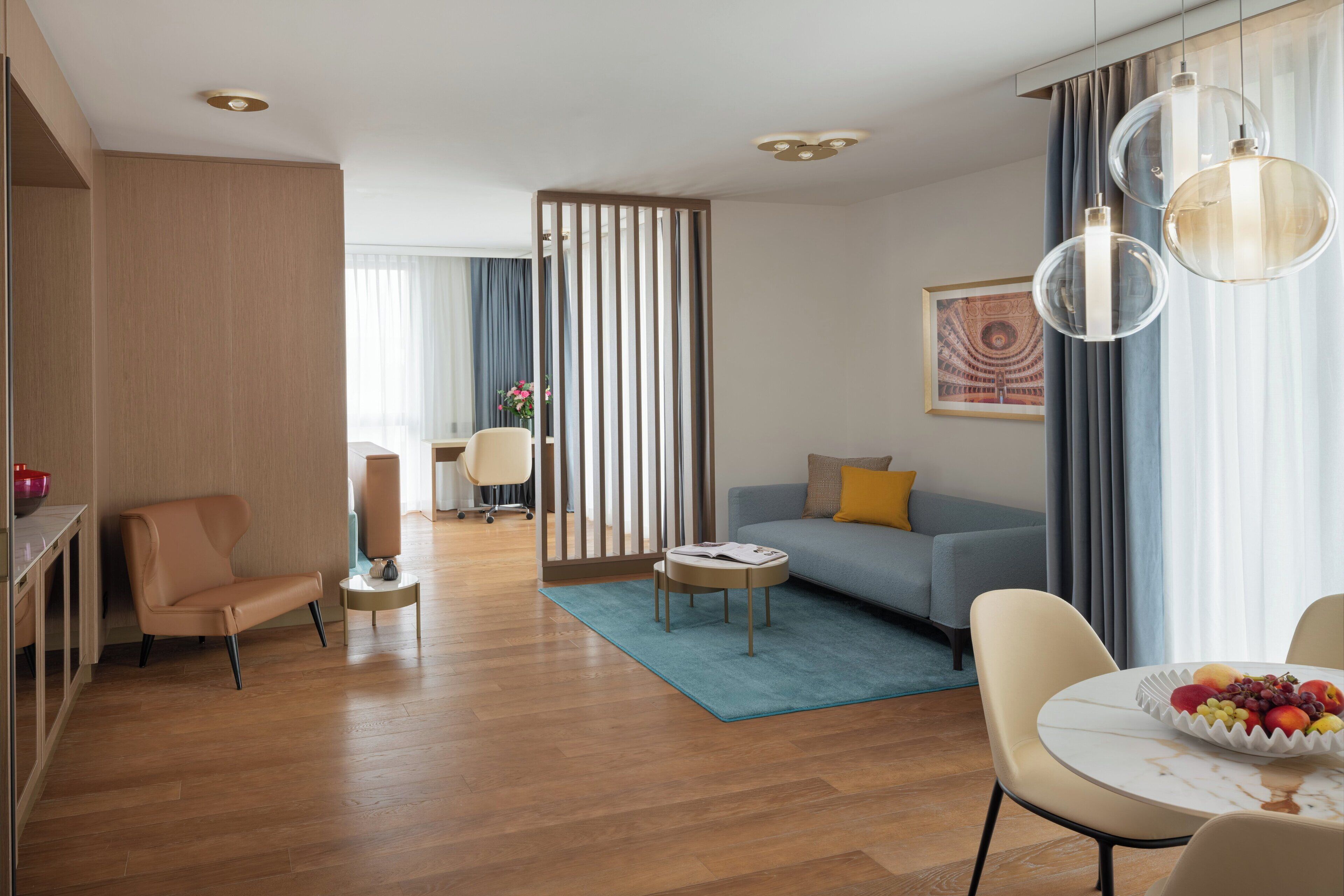 A modern living room with a sofa, chairs, a coffee table, and a dining table with fruit.