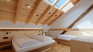 Un interior de madera con dos camas, un tragaluz y techo de madera.