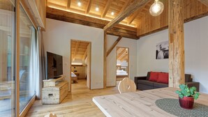 Un interior moderno con vigas de madera, una zona de comedor, un sofá y un televisor.