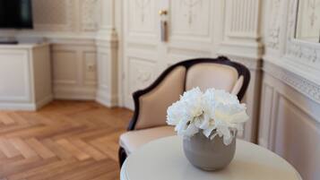 A room with a round table, a beige chair, and a vase with white flowers.