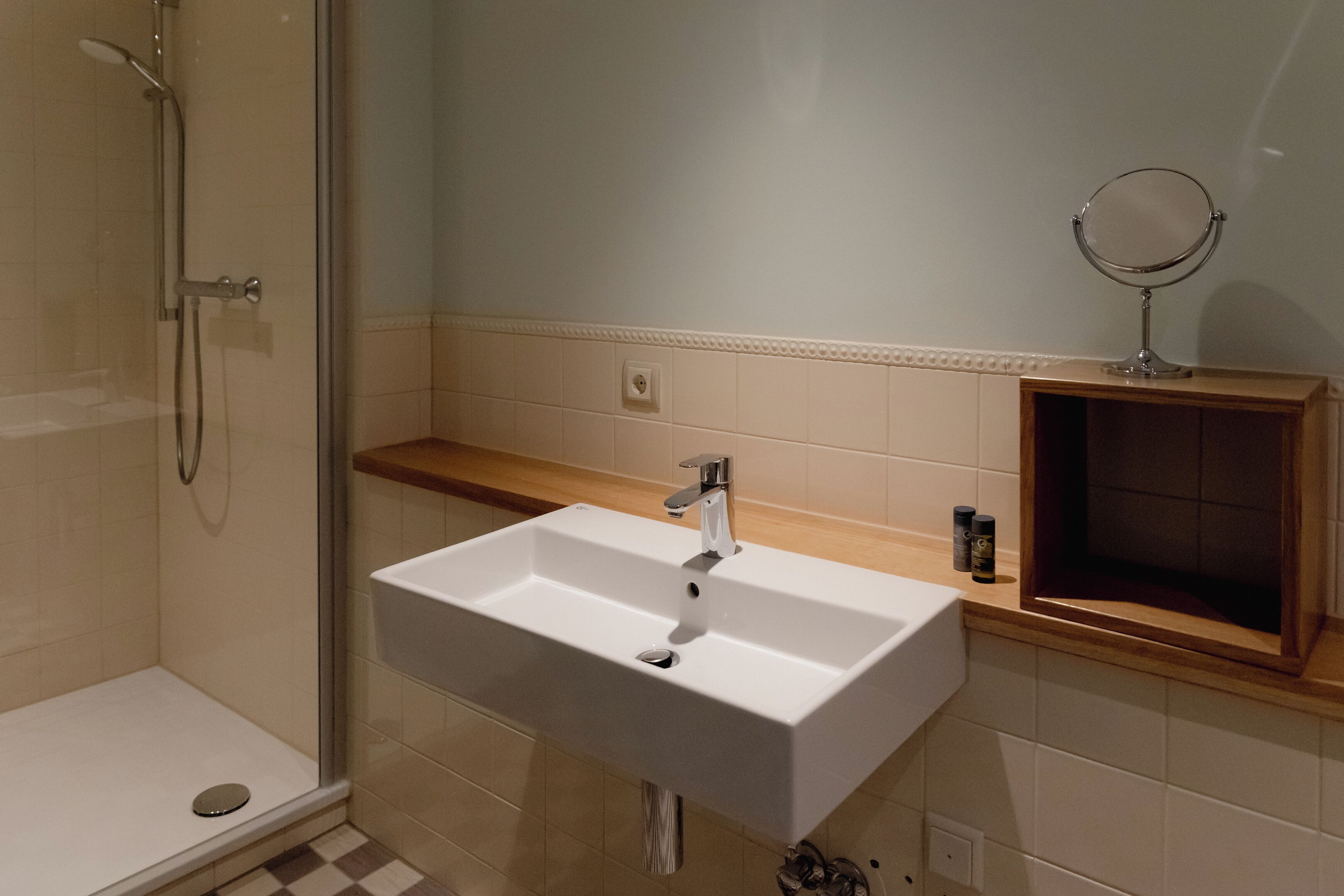 A bathroom with a white sink, a mirror, and a shower.