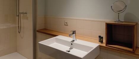 A bathroom with a white sink, a mirror, and a shower.