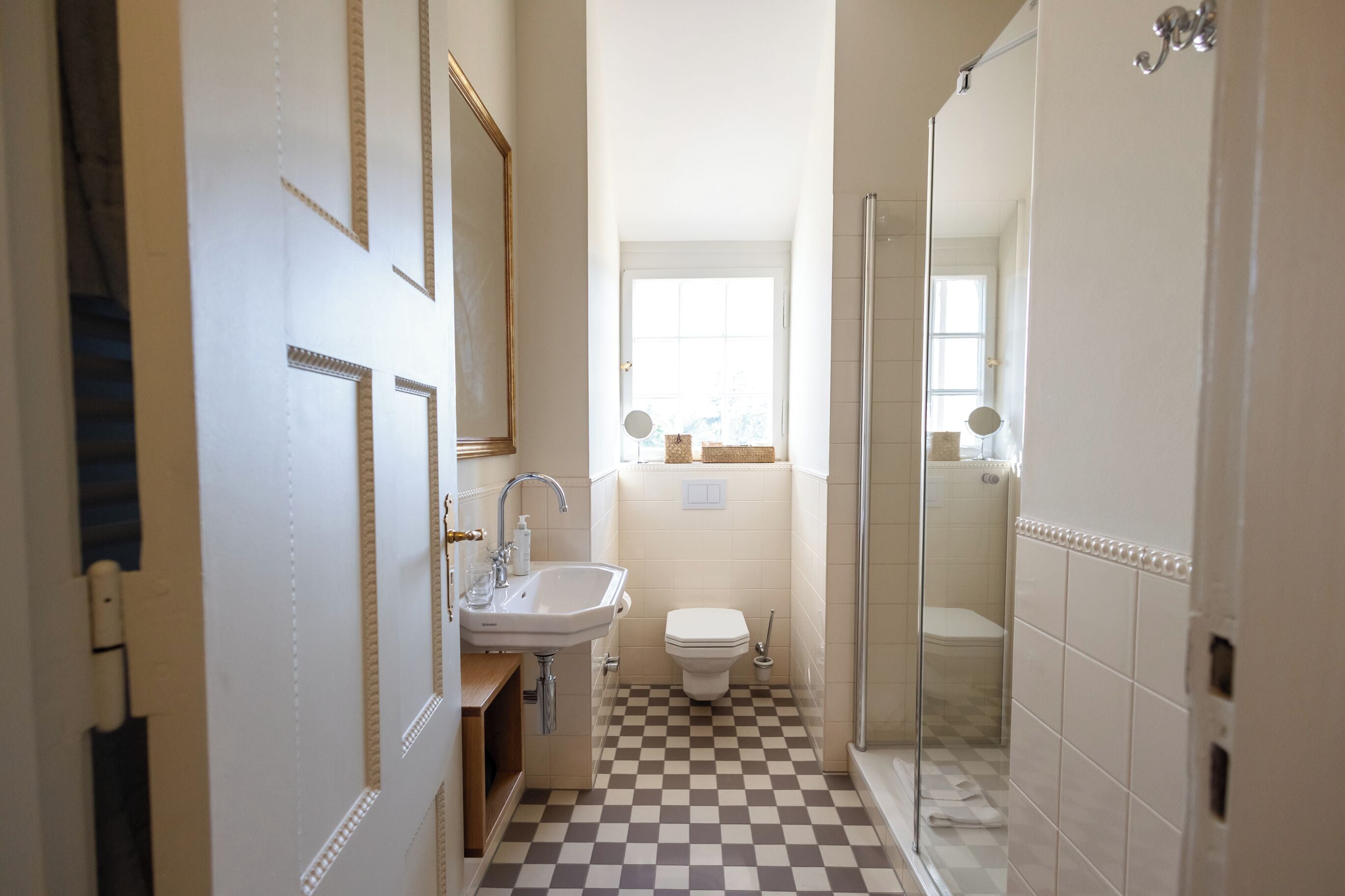 Un baño con piso de cuadros, un lavamanos, un inodoro y una ducha.