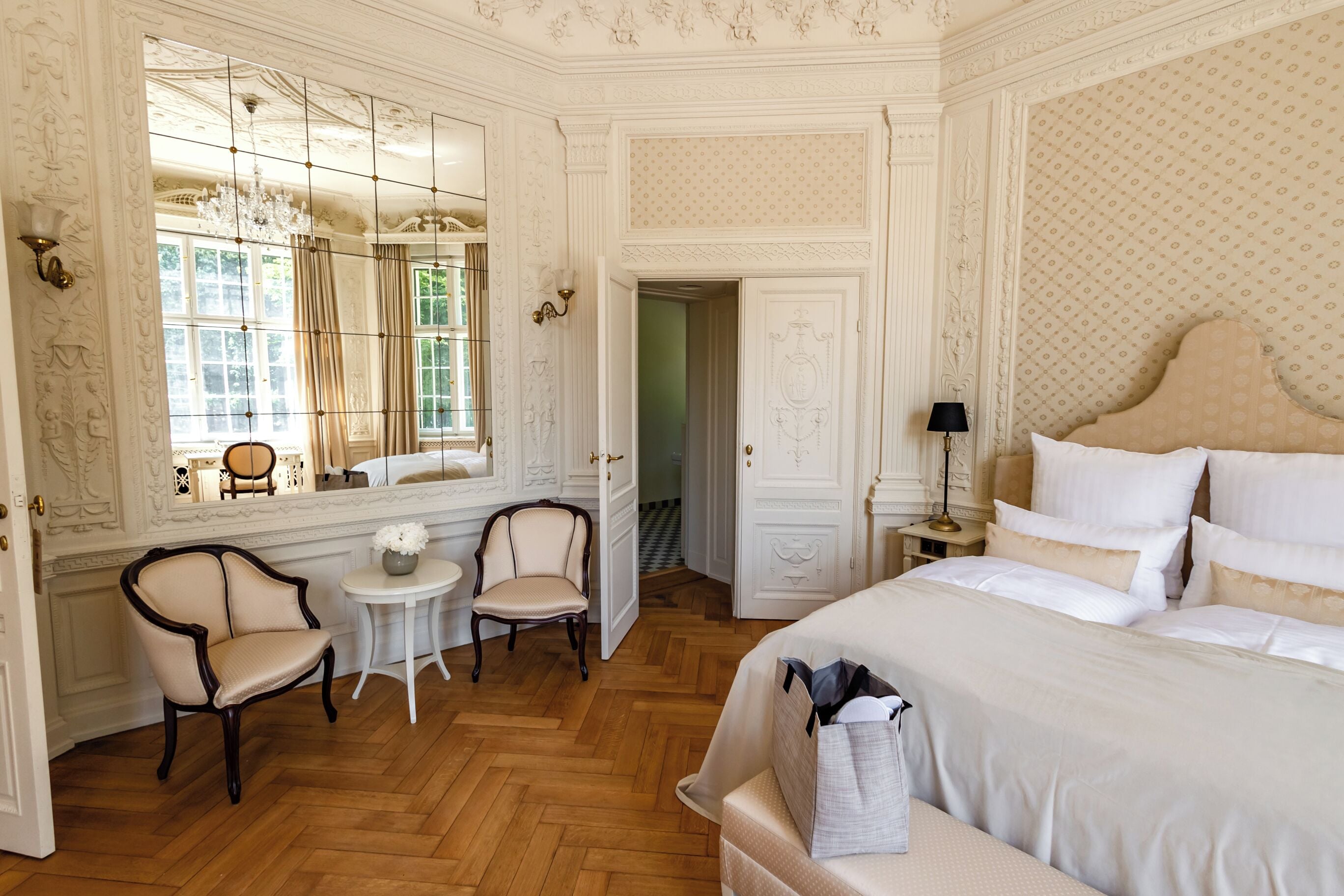 Une chambre classique avec un grand lit, une petite table, deux chaises et un miroir.