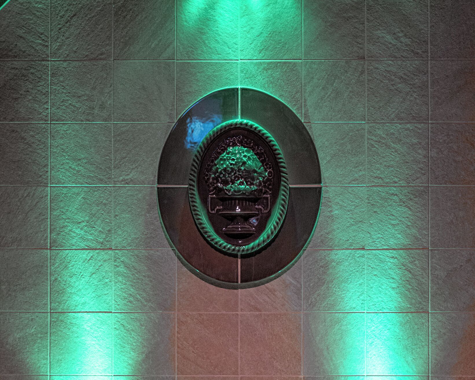 Un emblema circular con un diseño central sobre una pared de azulejos.