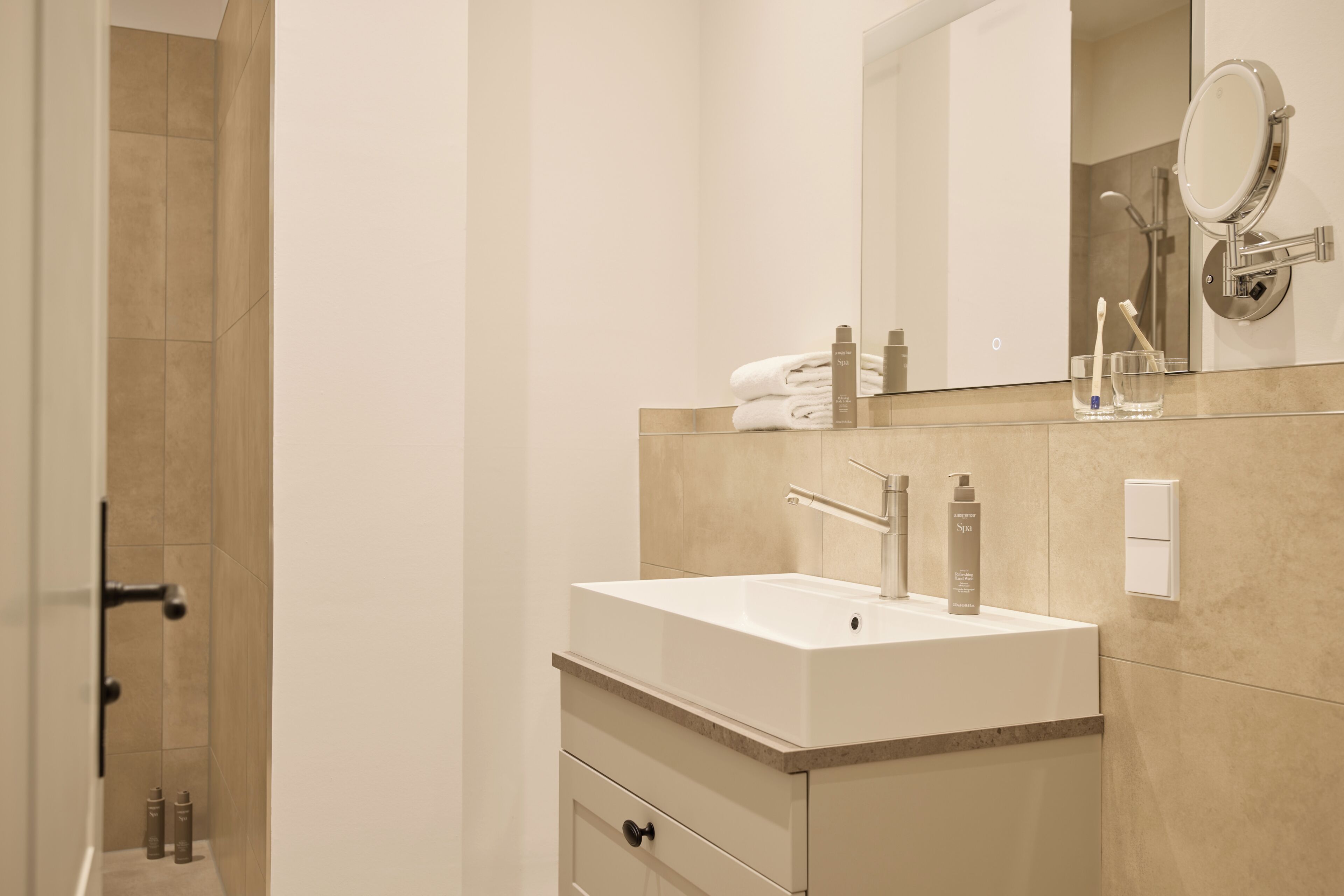 Ein modernes Badezimmer mit Waschbecken, Spiegel und Pflegeprodukten.