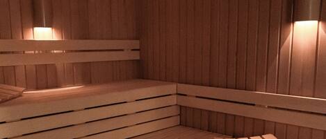 A sauna with wooden benches and wall-mounted lights.